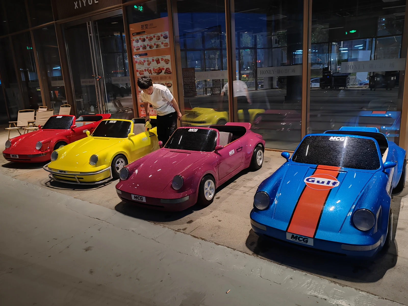 Red, yellow, pink and blue adult drift go karts displayed outside a venue
